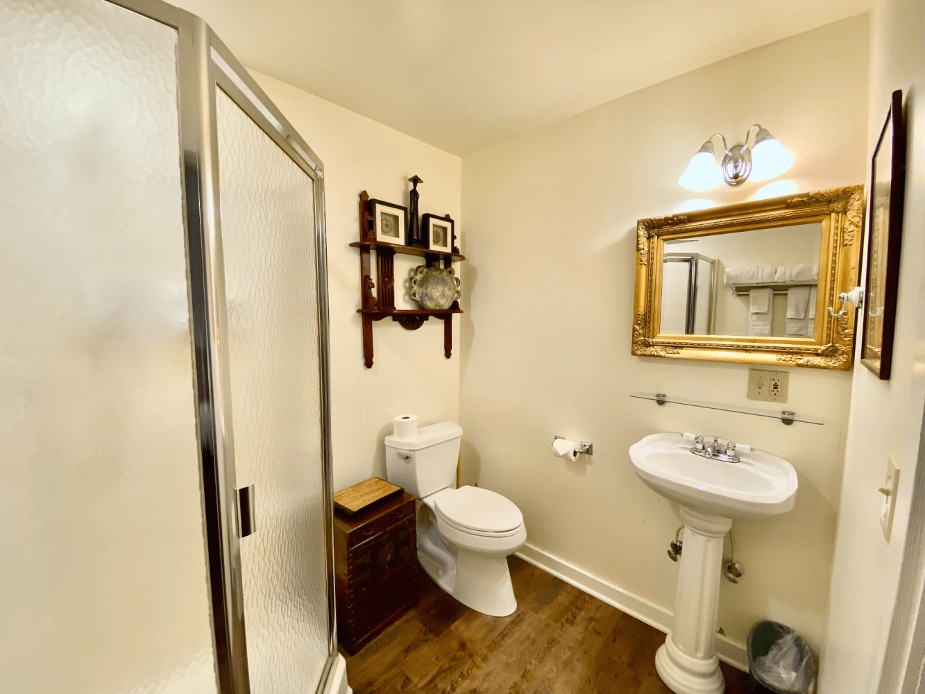 A bathroom with a toilet , sink , shower and mirror.