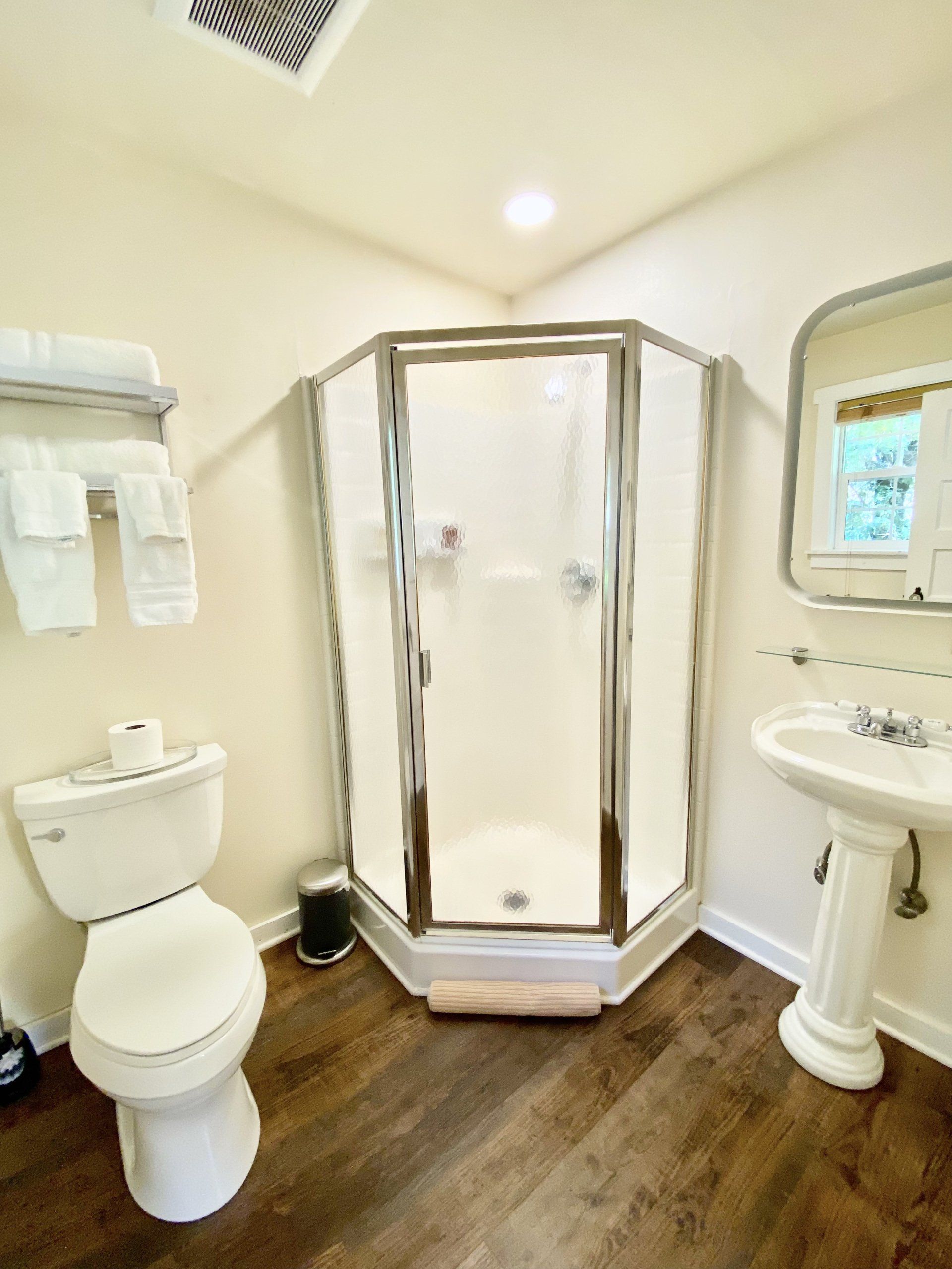 A bathroom with a toilet , sink and shower.