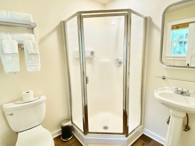 A bathroom with a toilet , sink , shower and mirror.