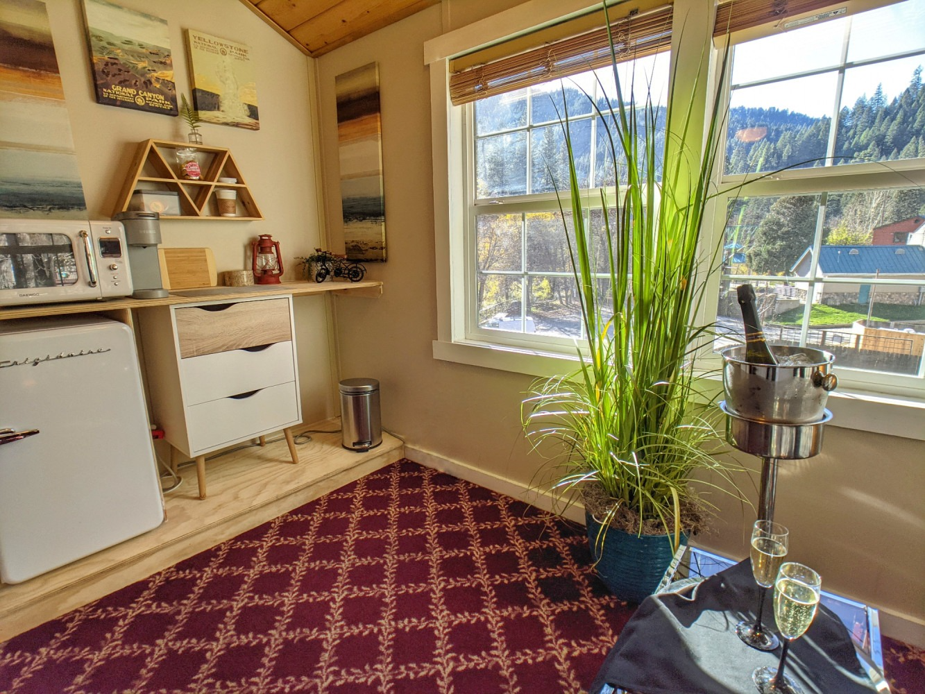 A room with a bottle of wine in a bucket on a table.