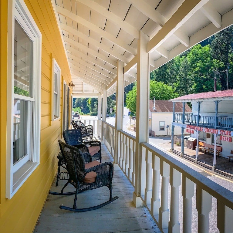 A yellow house has a porch with rocking chairs on it