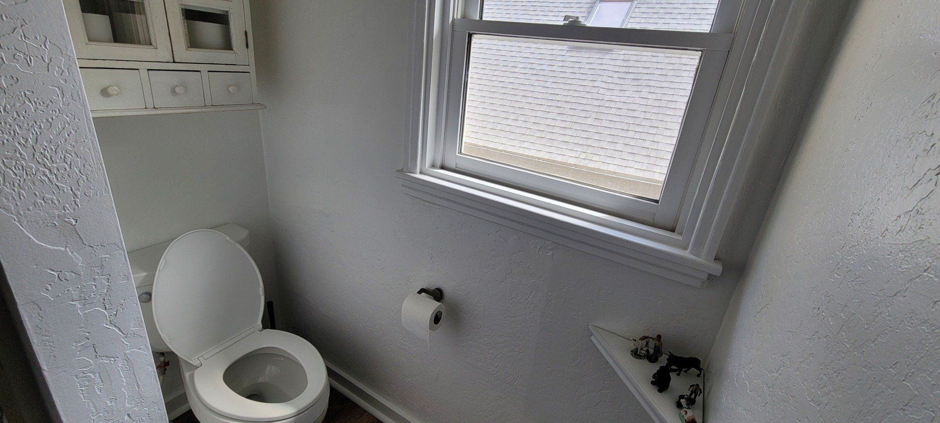 A small bathroom with a toilet and a window.