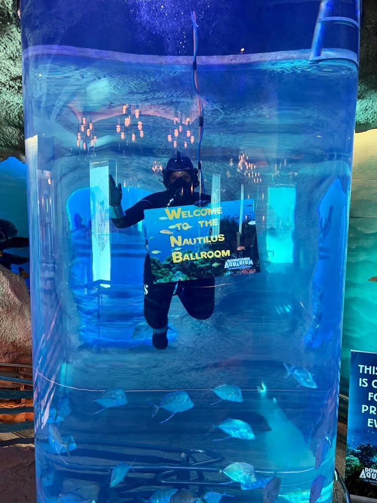 A man is swimming in a tank with a sign that says welcome to the nautilus ballroom