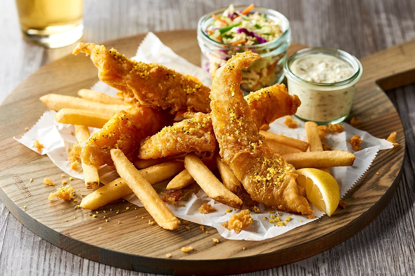 A wooden cutting board topped with fried fish and french fries