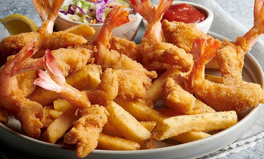 A plate of fried shrimp and french fries with coleslaw and ketchup.