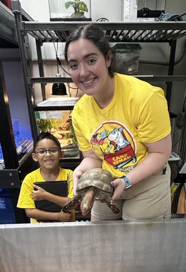 A man in a yellow shirt with a parrot painting a picture