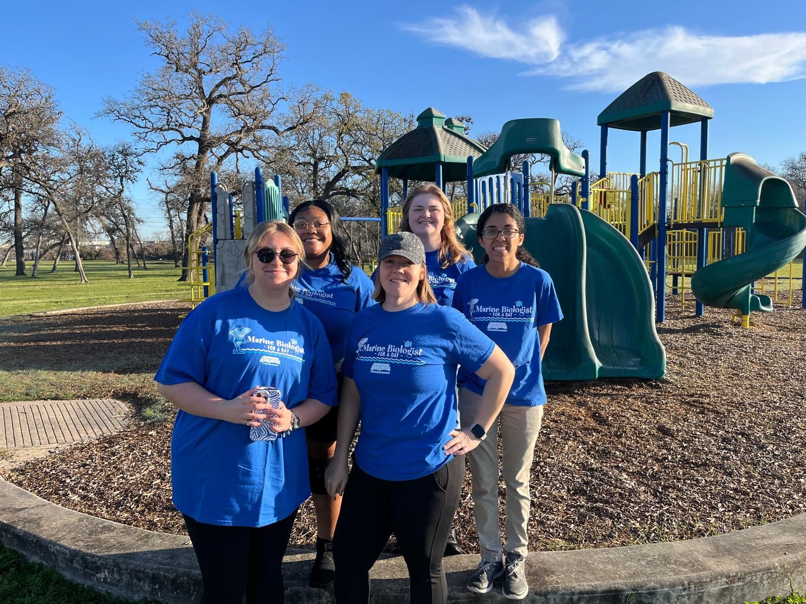 A group of women are posing for a picture in front of a playground