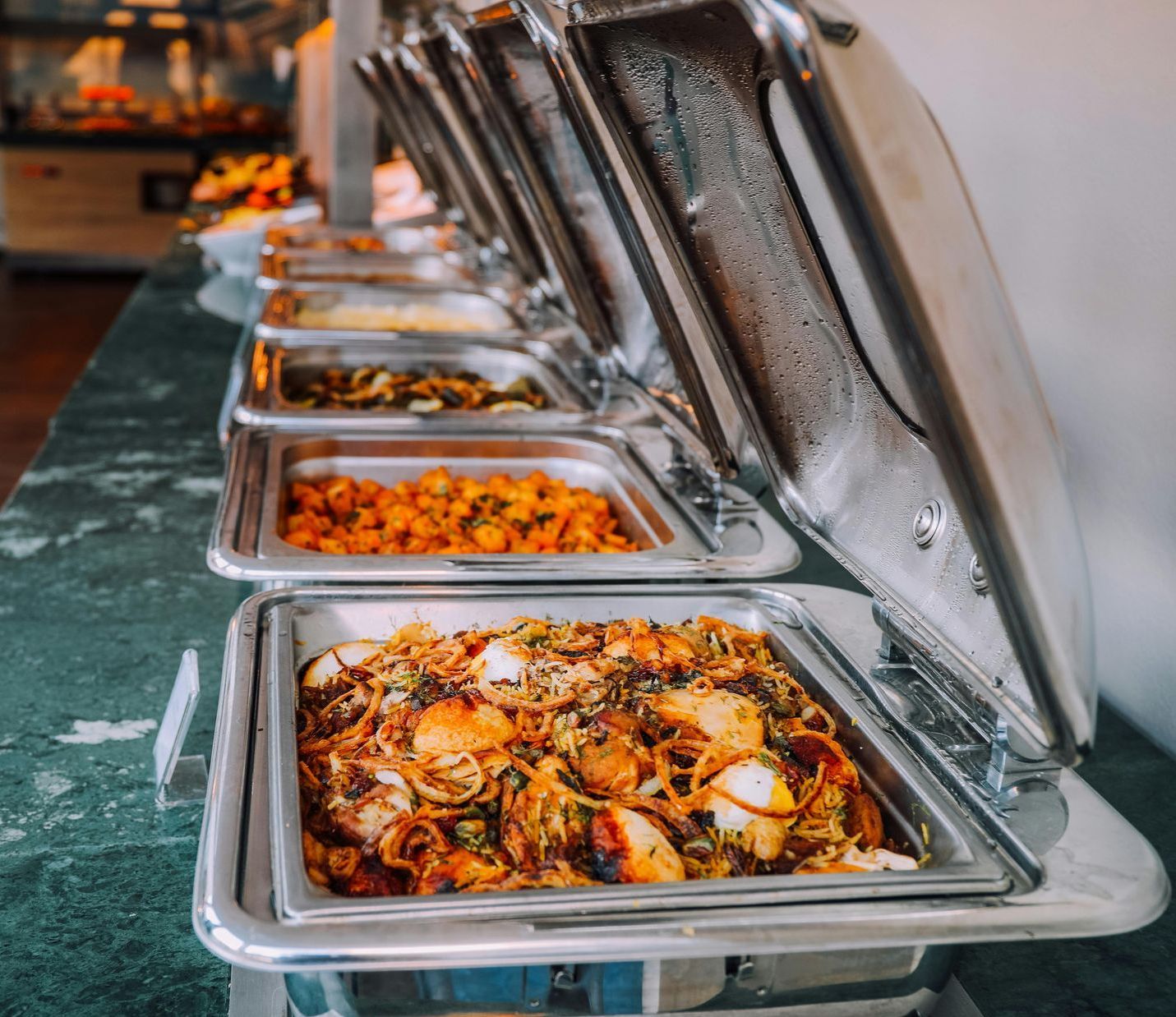 A buffet line with many trays of food on it