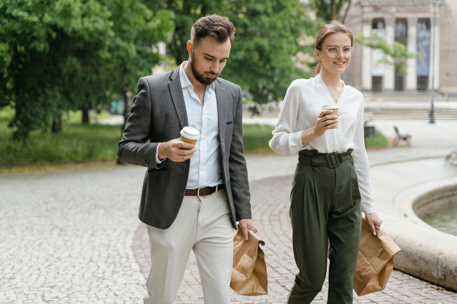 A man and a woman are walking down a sidewalk.