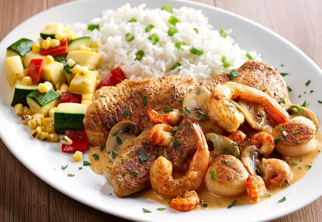 A white plate topped with shrimp rice and vegetables
