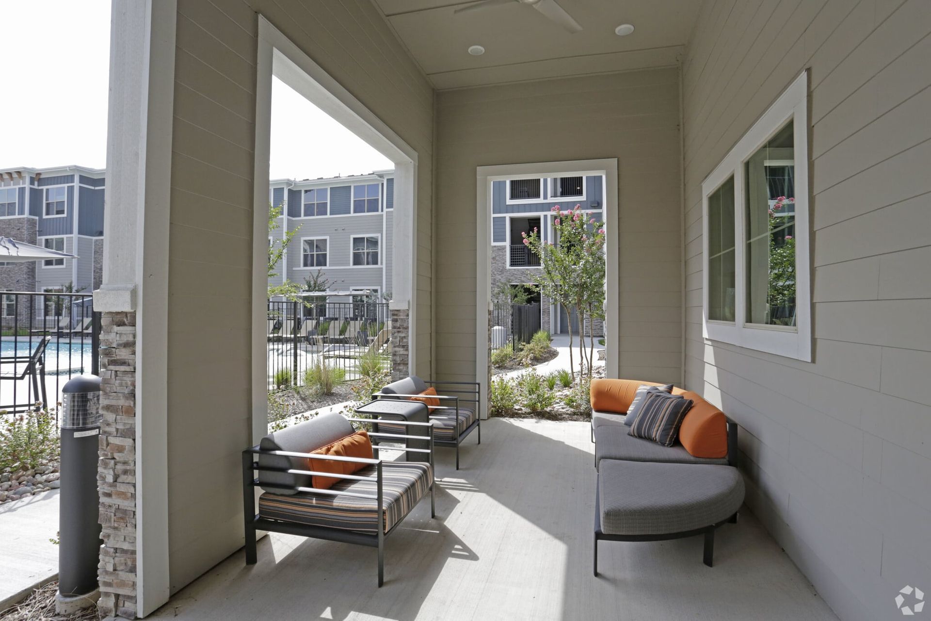 Covered patio with modern outdoor seating and a pool in the background.