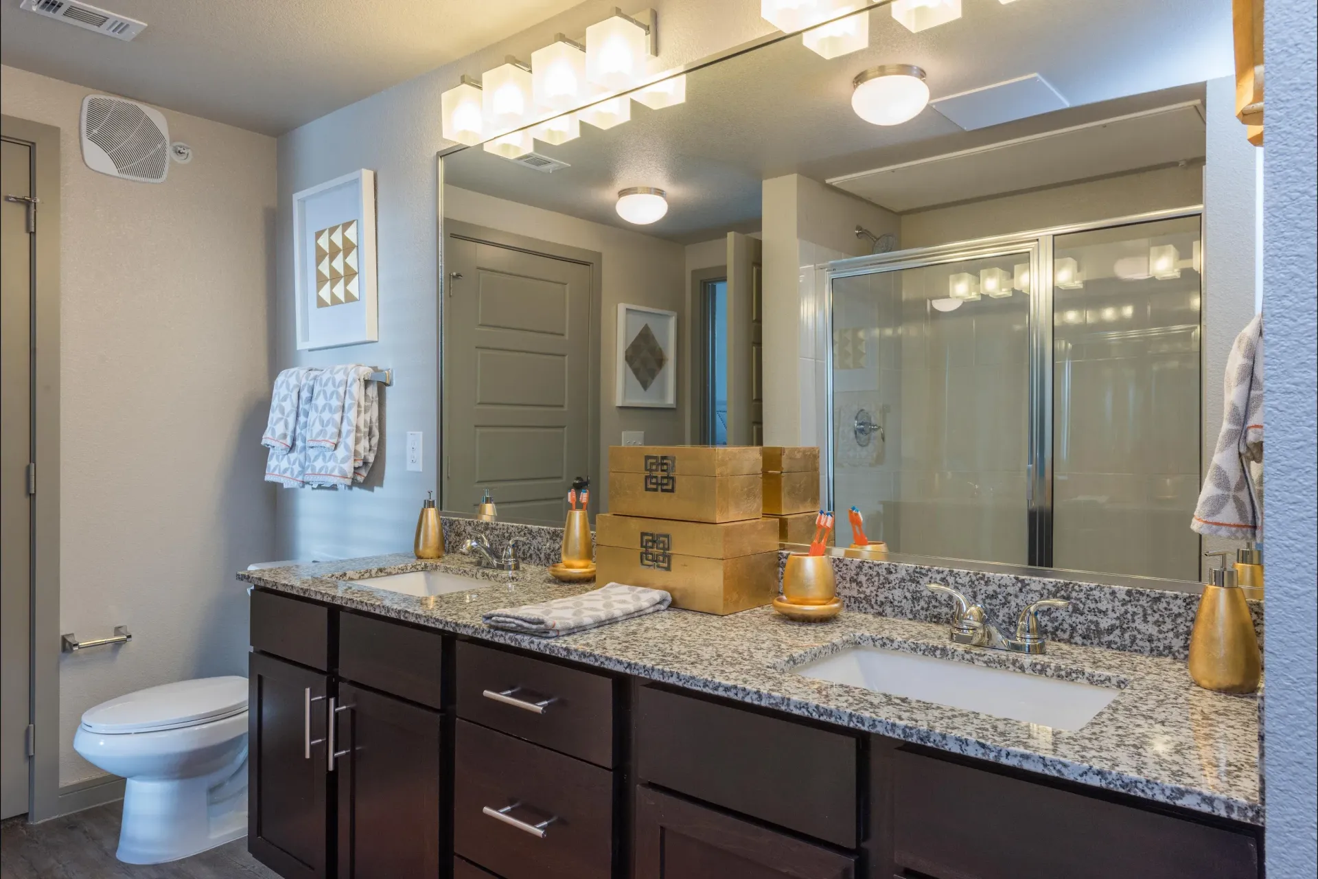 Bathroom with a dual-sink granite vanity, large mirror, and glass shower.