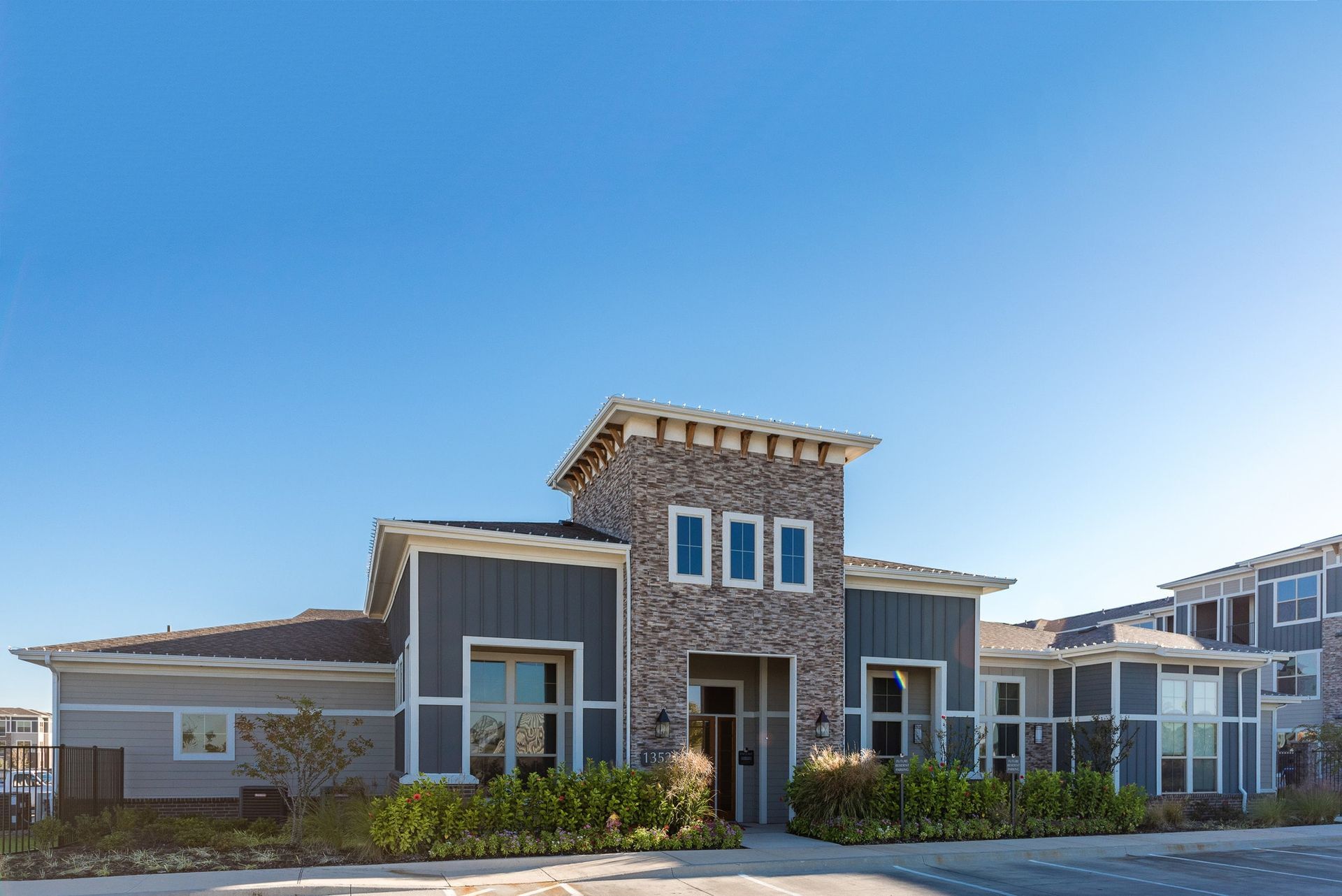 Exterior view of a modern multifamily building with stone facade and landscaped entry.