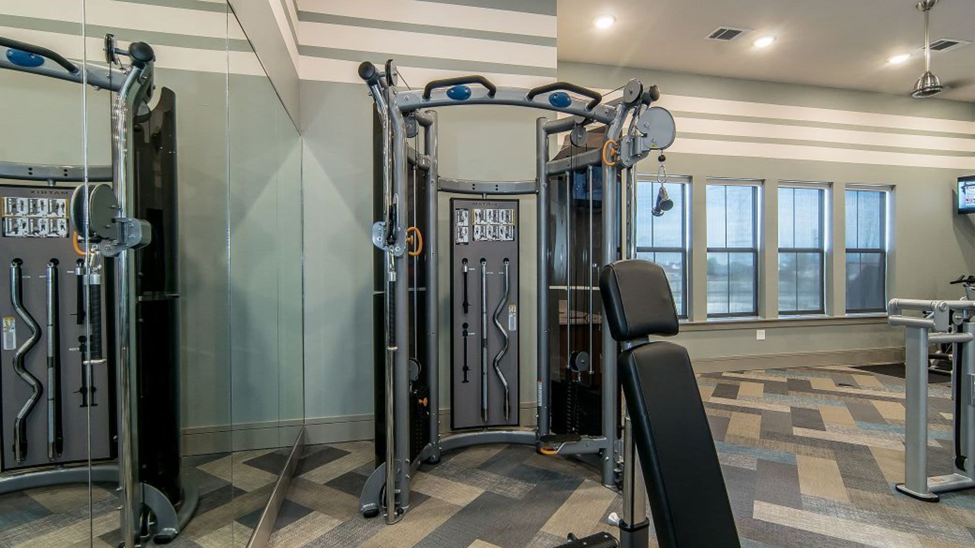 Interior of apartment gym with weight machine and bench.