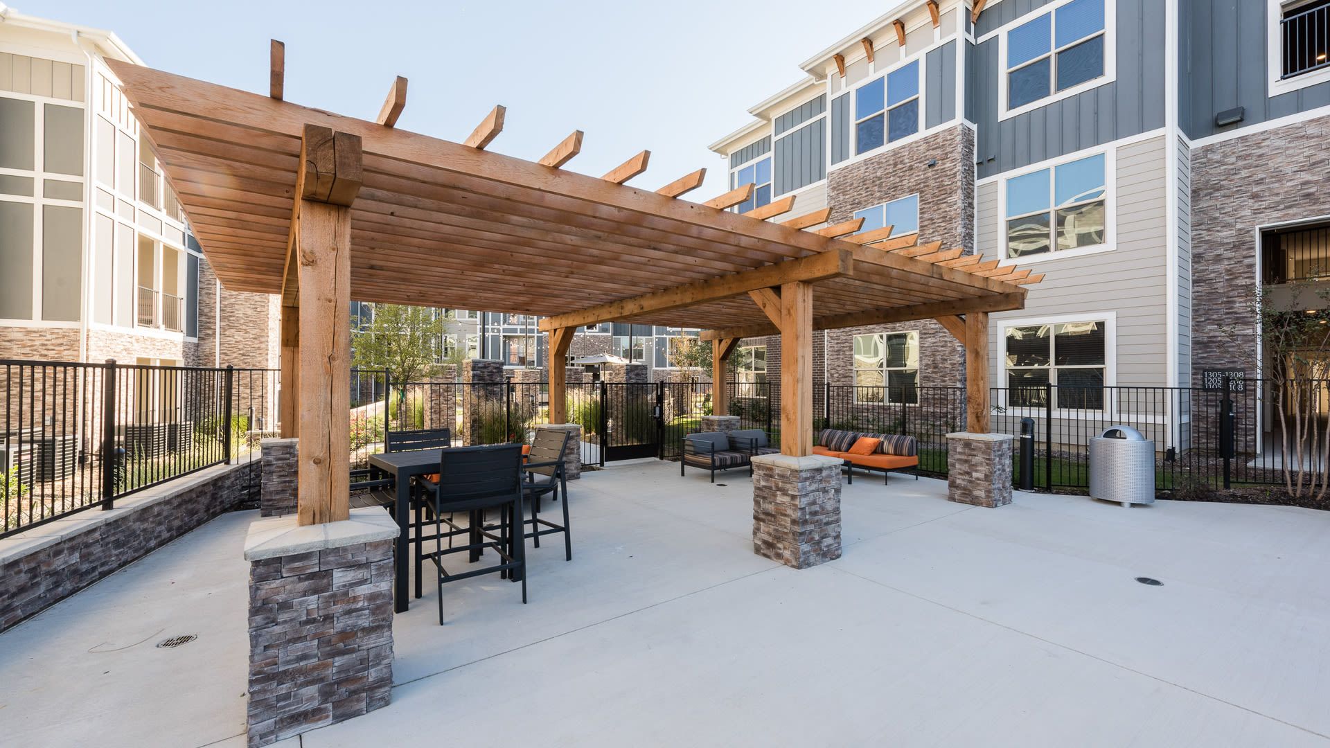 Outdoor communal seating under a wooden pergola in an apartment courtyard.