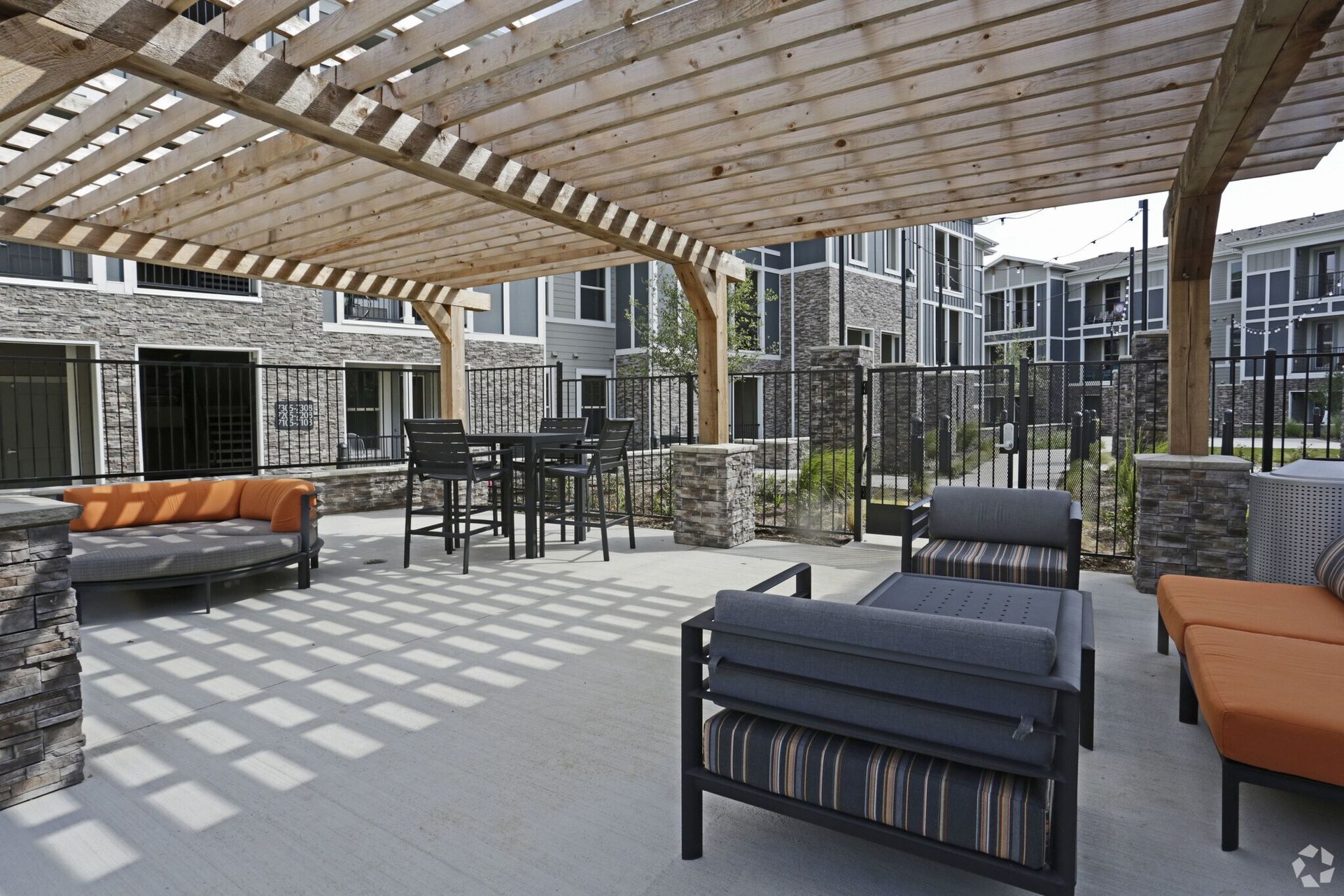 Outdoor community courtyard with a wooden pergola, lounge seating, and dining table.