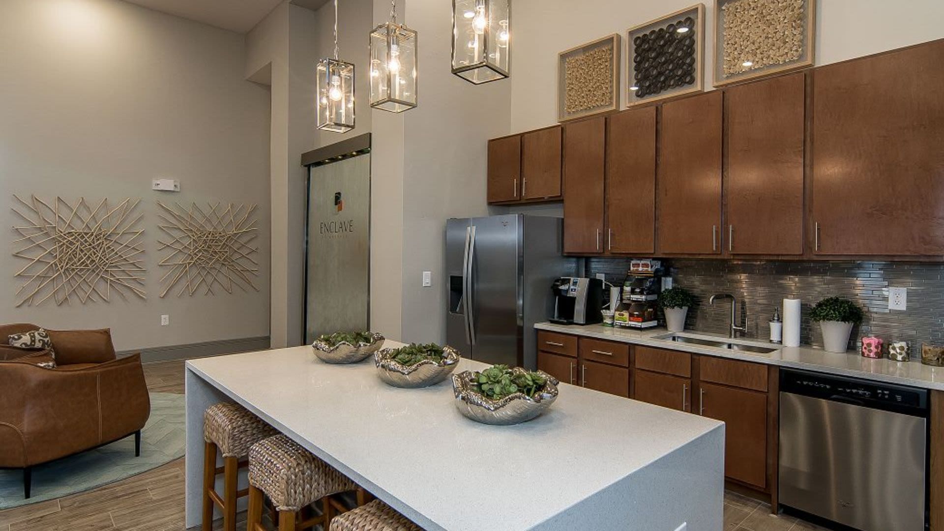 Modern community kitchenette with island, pendant lighting, and stainless appliances.