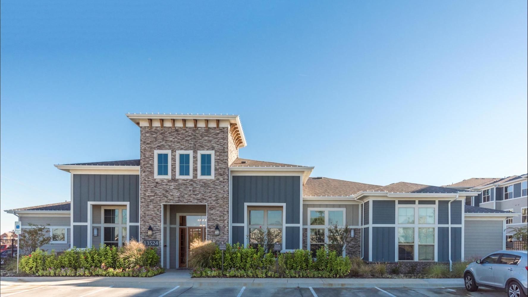 Exterior view of a modern multifamily building with stone facade and landscaped front.
