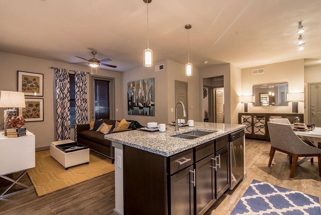 Open-concept kitchen with granite island and stainless-steel appliances adjoining living area.