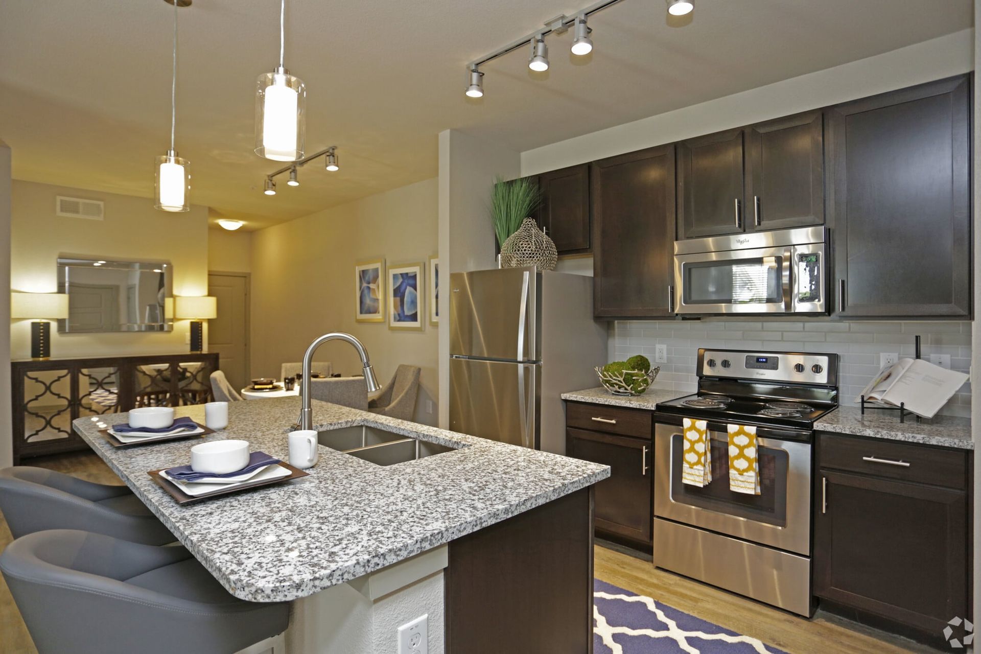 Modern kitchen with granite counter island, stainless steel appliances, and pendant lighting.