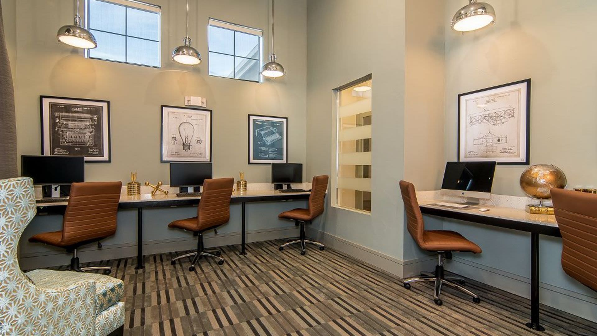 Interior view of a resident community computer center with four workstations and brown chairs.