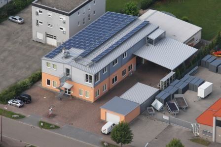 Eine Luftaufnahme eines Gebäudes mit Solarmodulen auf dem Dach.