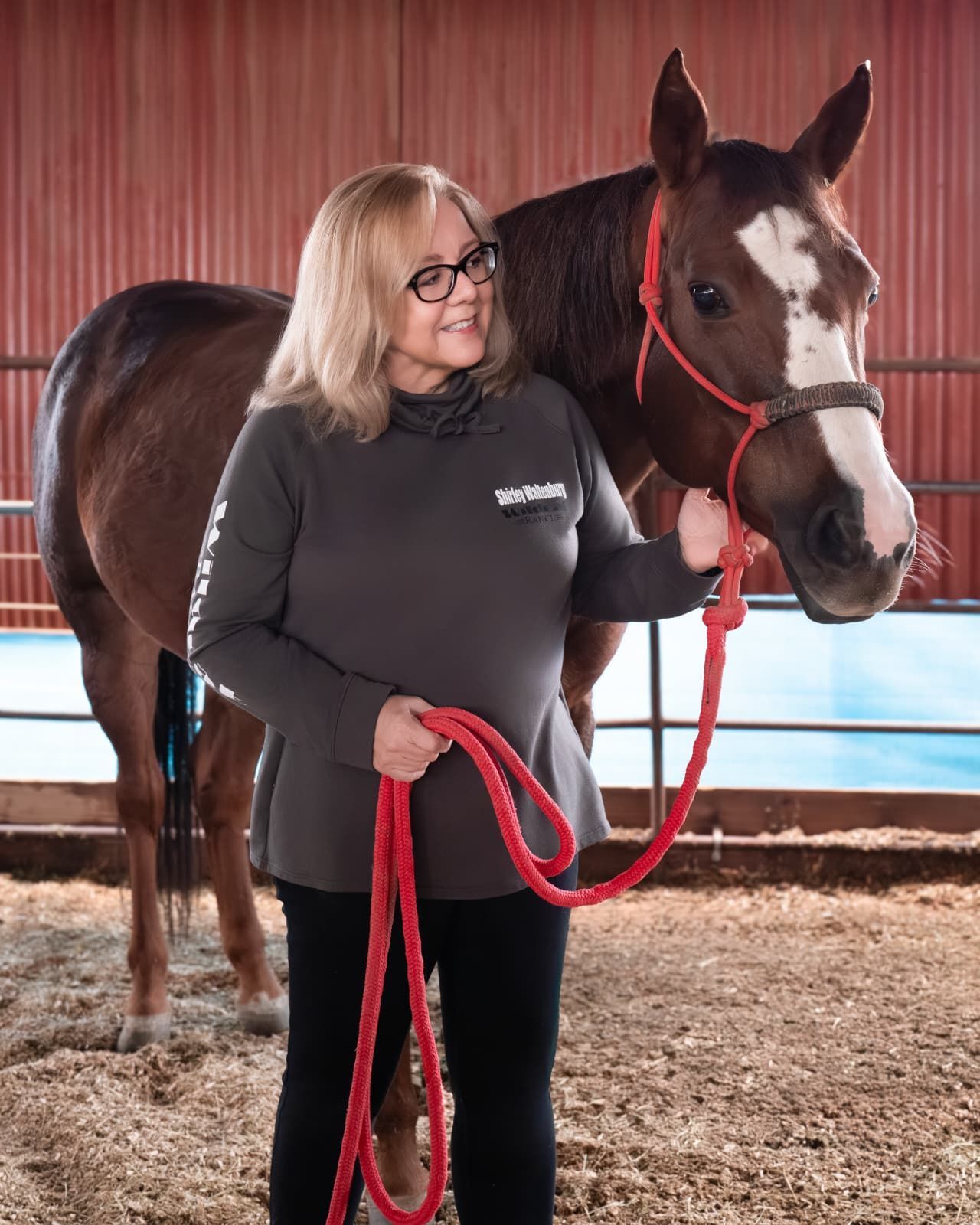 A man in a yellow vest is adjusting a thermostat while holding a tablet.