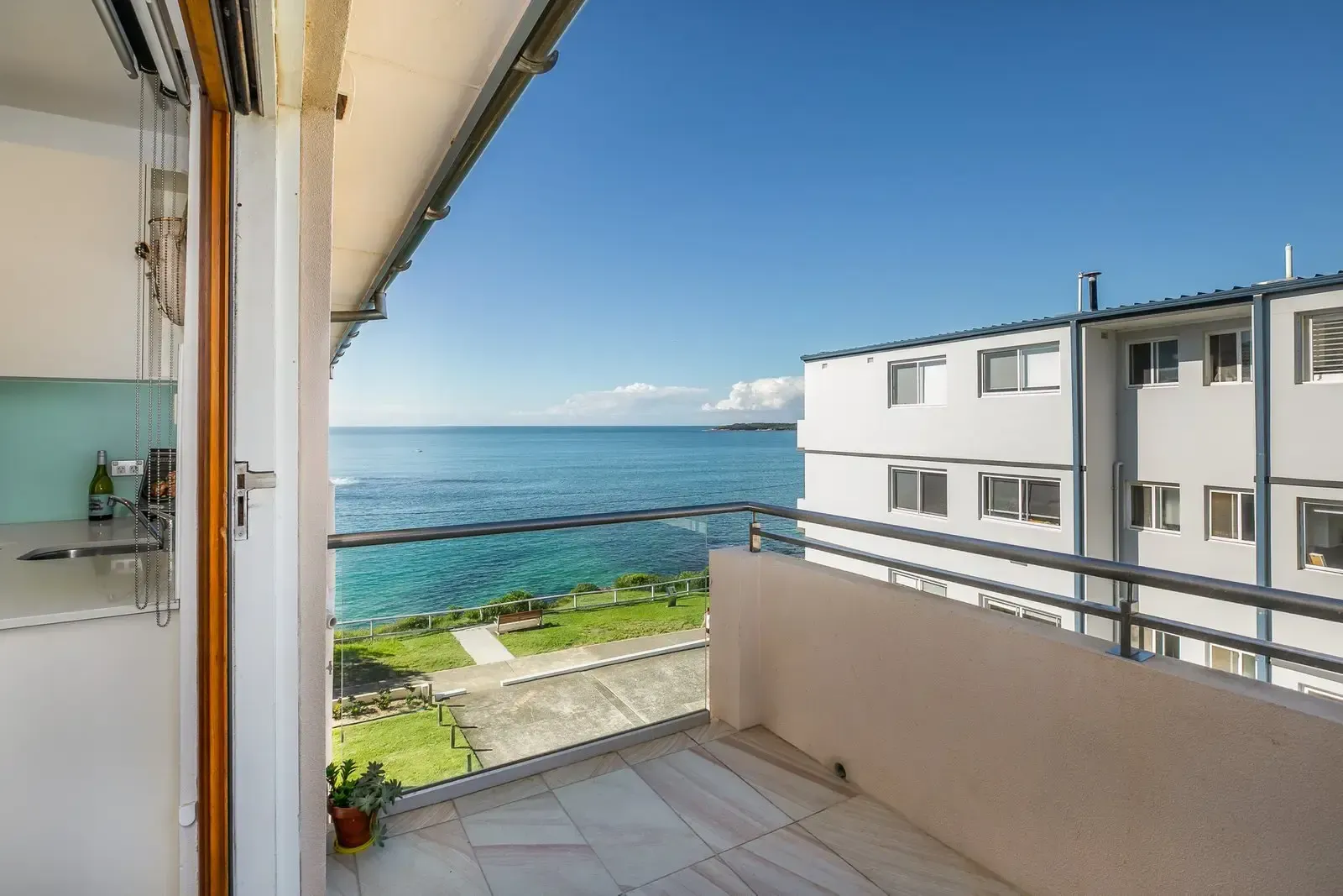 A balcony with a view of the ocean and a building in the background.