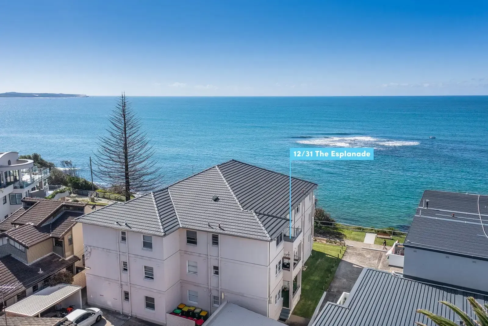 An aerial view of a house on a cliff overlooking the ocean.