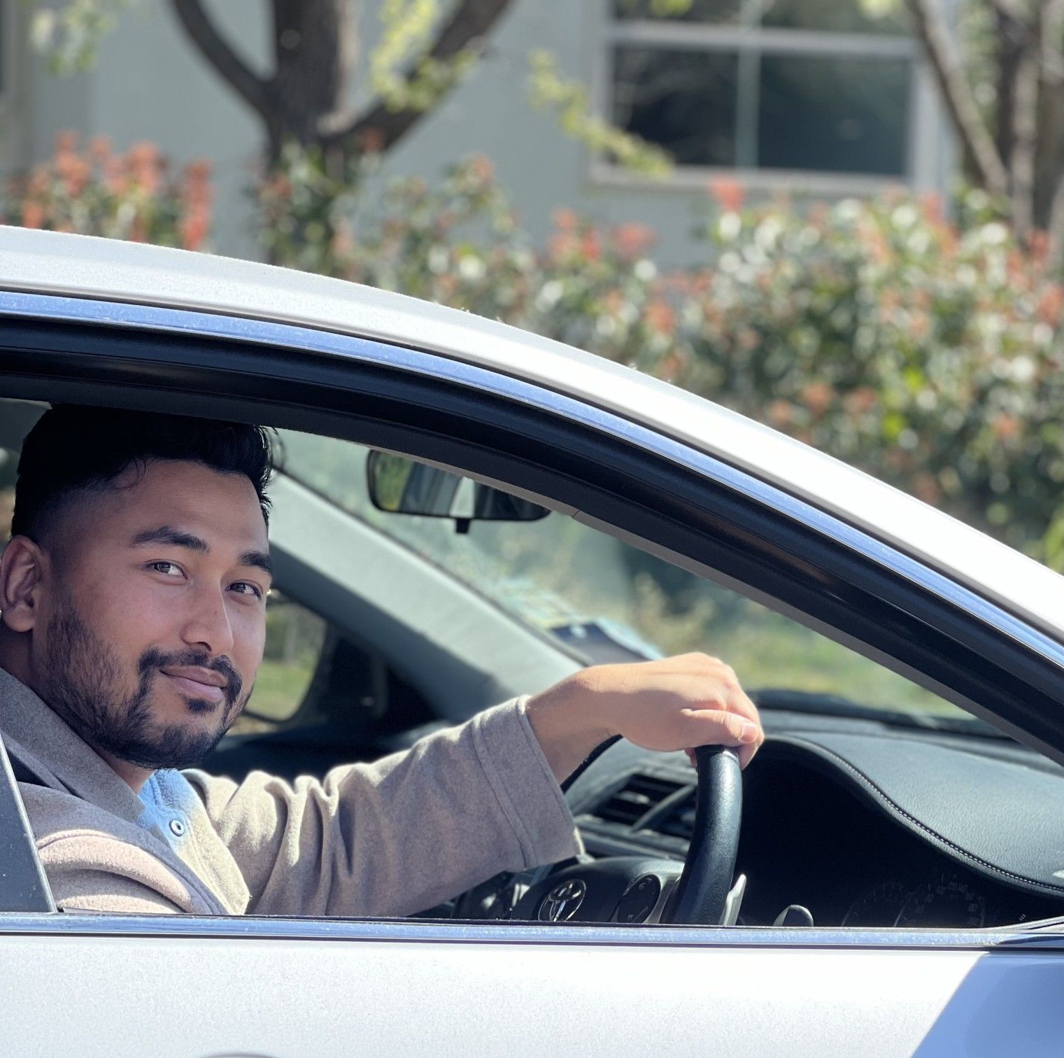 A man is sitting in a car holding the steering wheel