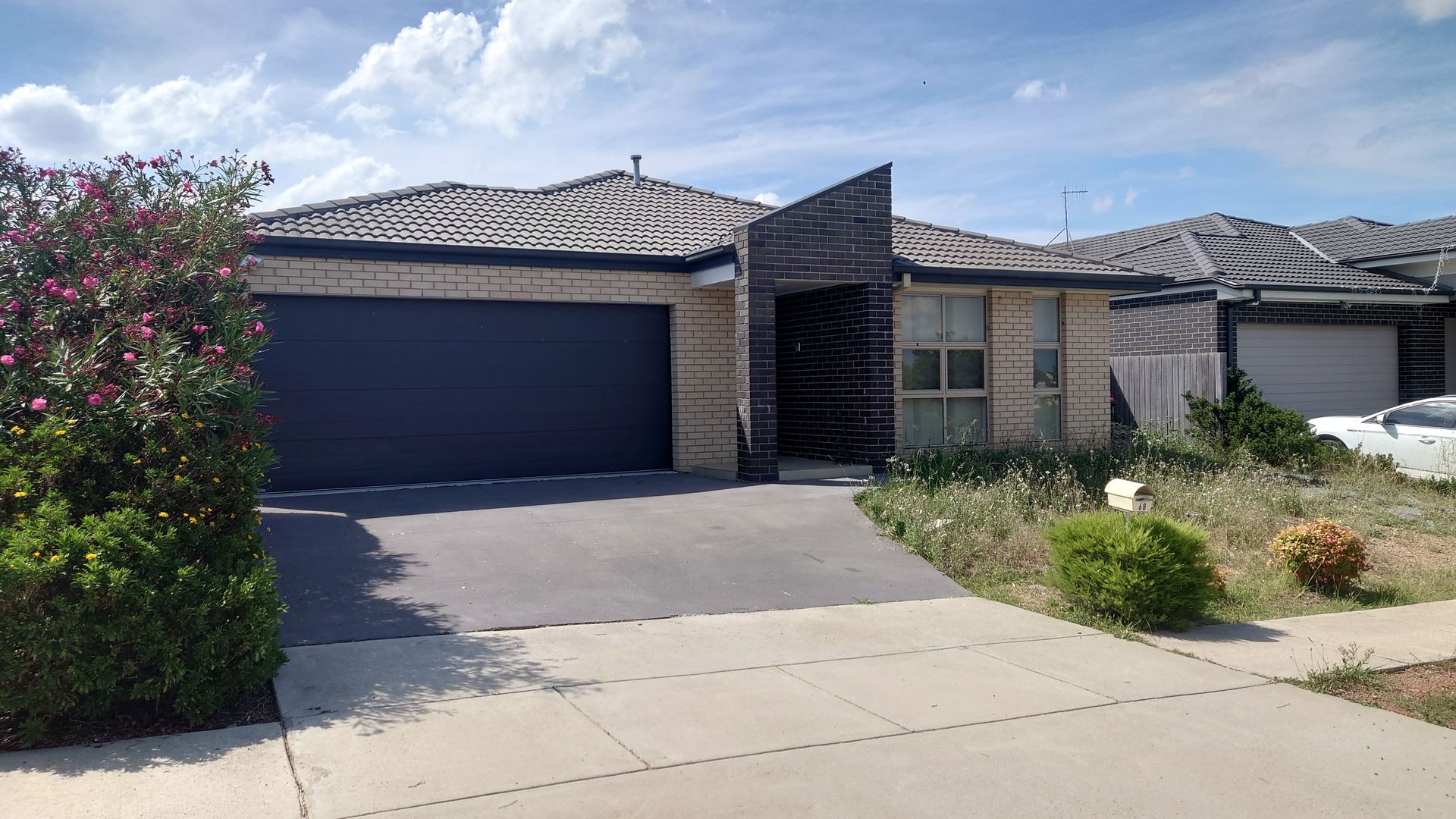 A house with a black garage door and a white car parked in front of it.
