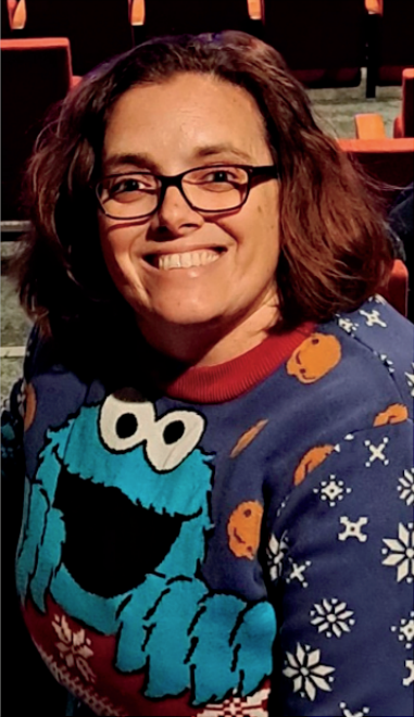 A woman wearing glasses and a cookie monster sweater