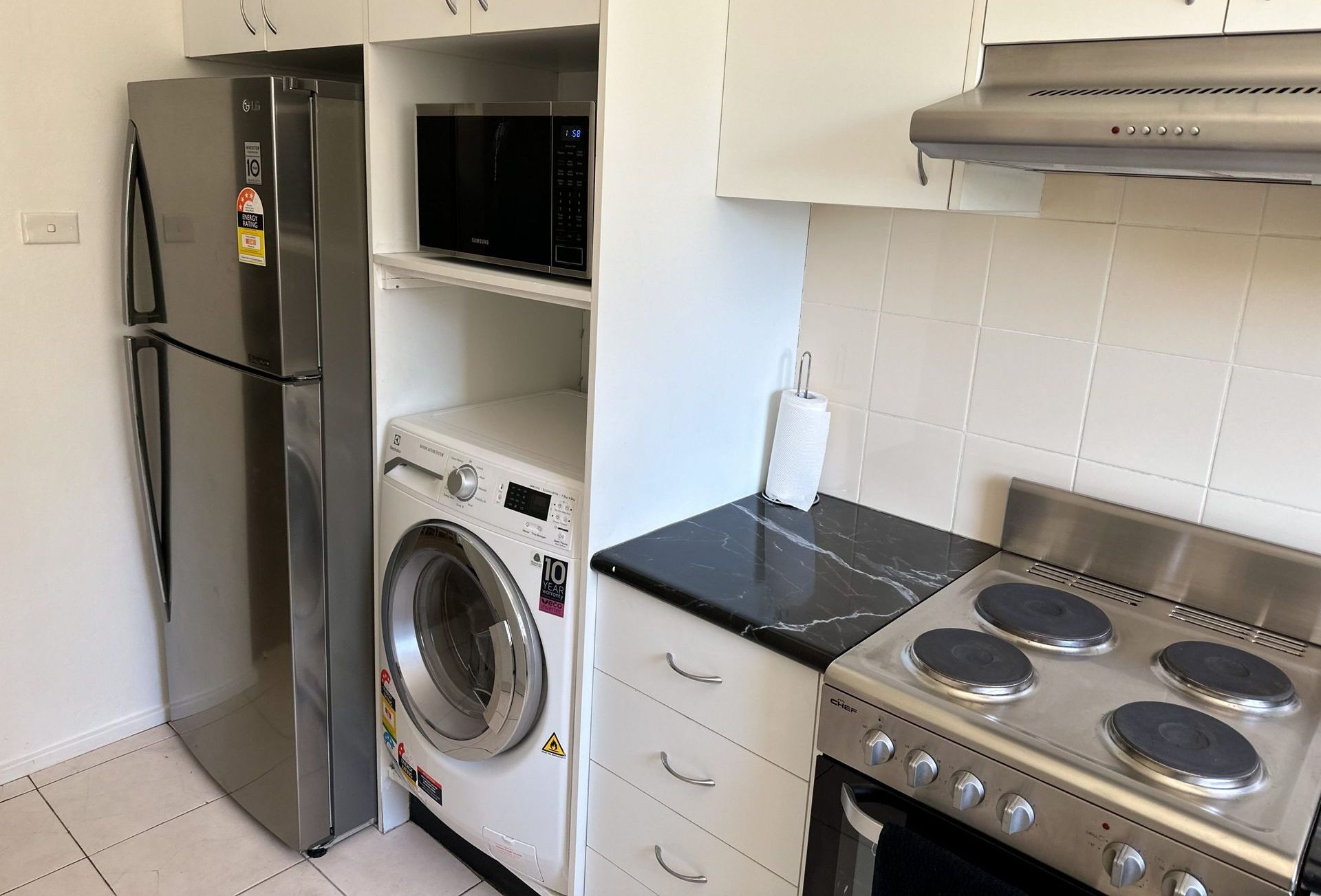 A kitchen with a stove , refrigerator , washer and dryer
