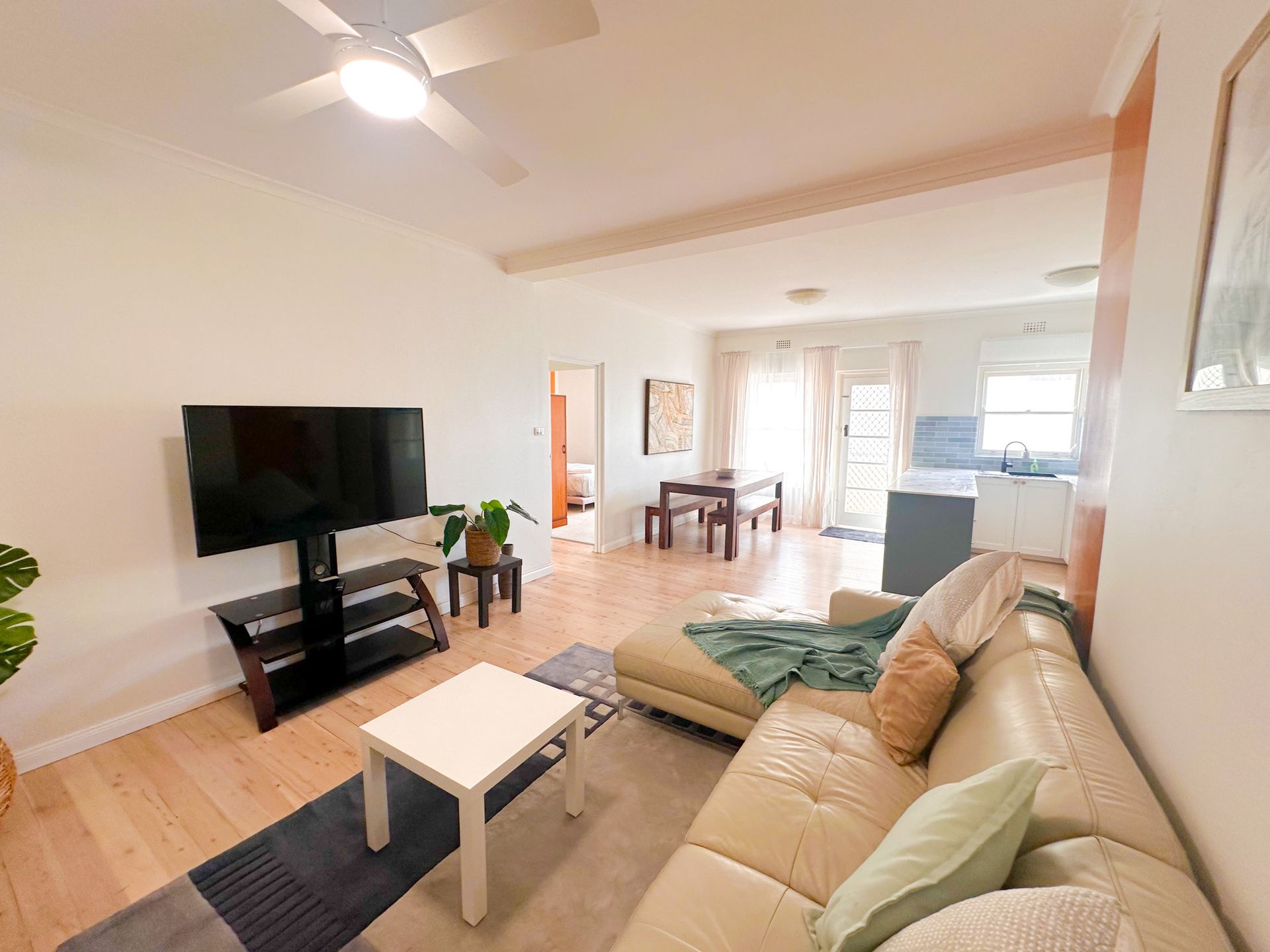 A living room with a couch , table , television and a ceiling fan.