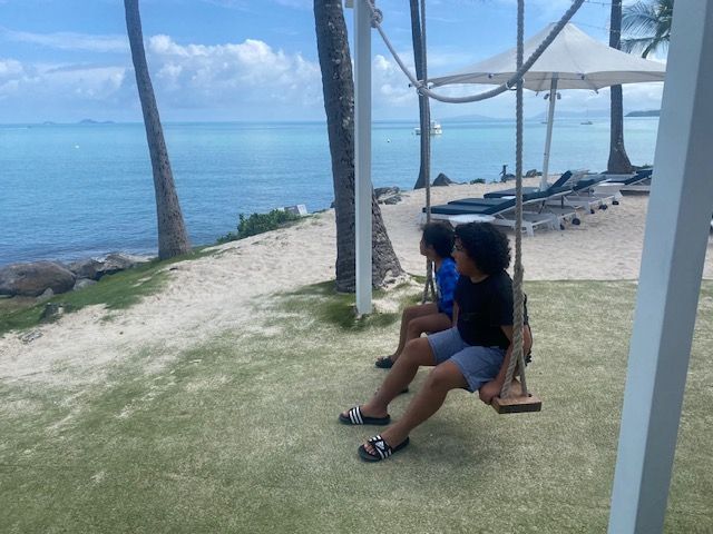 Two children are sitting on a swing overlooking the ocean