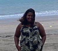 A woman in a dress is standing on a beach.