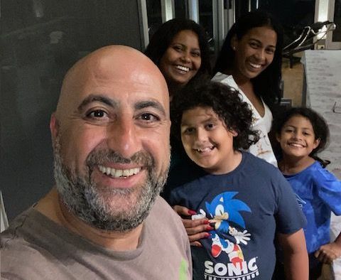 A man wearing a sonic the hedgehog shirt is posing for a picture with his family.