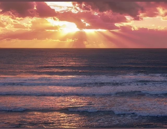 The sun is shining through the clouds over the ocean