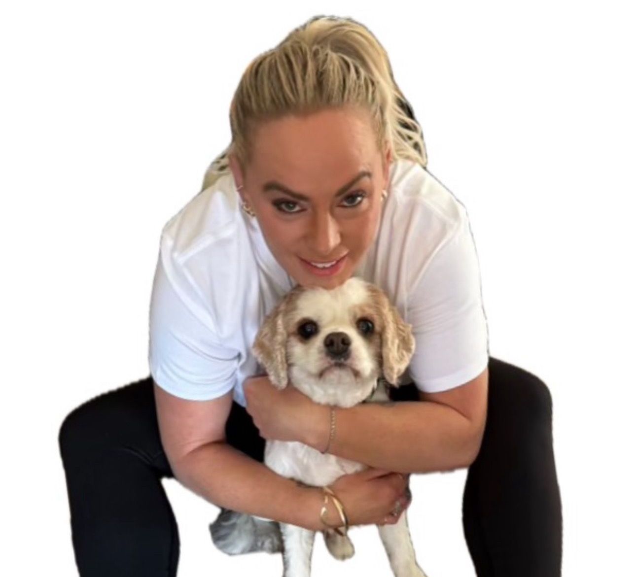 A woman is kneeling down holding a small dog