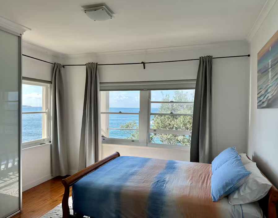 A bedroom with a bed and a window overlooking the ocean.