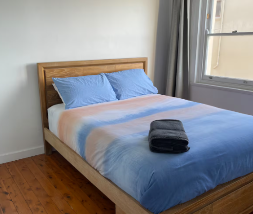 A bed with a blue comforter and pillows in a bedroom