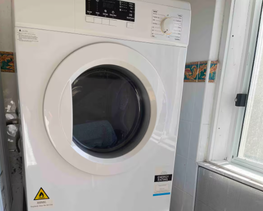 A white washing machine and dryer are sitting in a room next to a window.