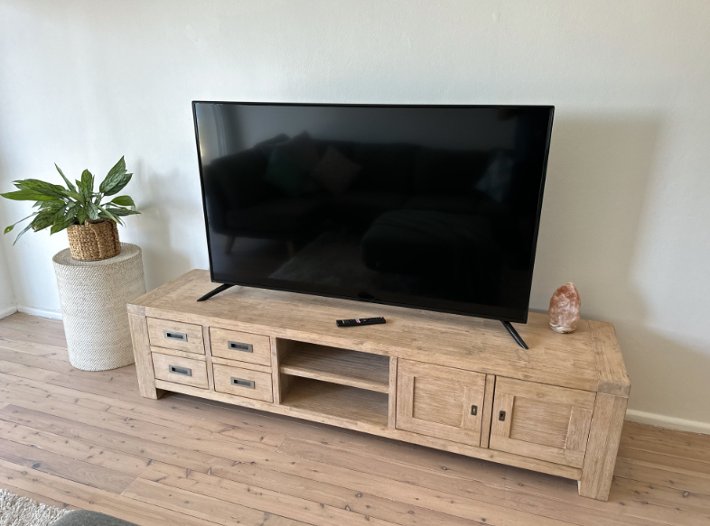 A flat screen tv is sitting on top of a wooden entertainment center in a living room.