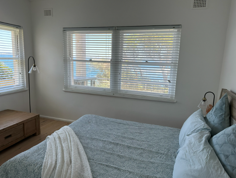 A bedroom with a bed , two windows and a lamp.