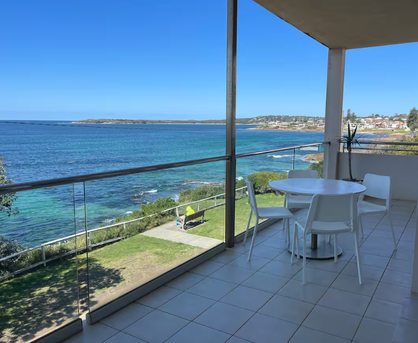 A balcony with a table and chairs overlooking the ocean