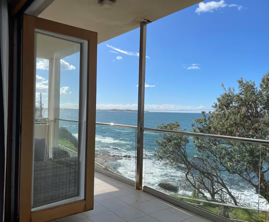 A balcony with a view of the ocean and trees