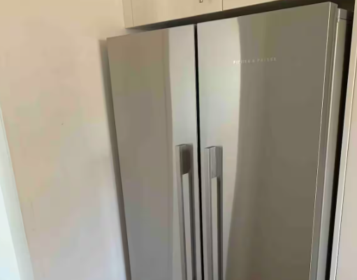 A stainless steel refrigerator is sitting in a kitchen next to a wall.