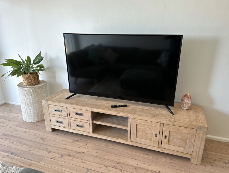 A flat screen tv is sitting on top of a wooden entertainment center in a living room.