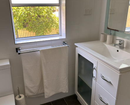 A bathroom with a sink , toilet , mirror and window.