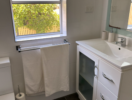 A bathroom with a sink , toilet , mirror and window.